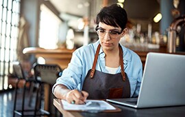 female restaurant barista on a laptop taking time to communicate with restaurant followers and patrons online.