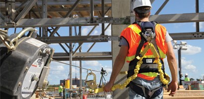Worker on worksite wearing harness and fall protection gear

