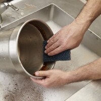 Un primer plano de una persona lavando un cuenco con la fibra de uso rudo de 3M.