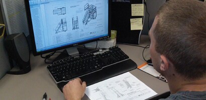 Engineer at computer looking at schematics of fall protection system
