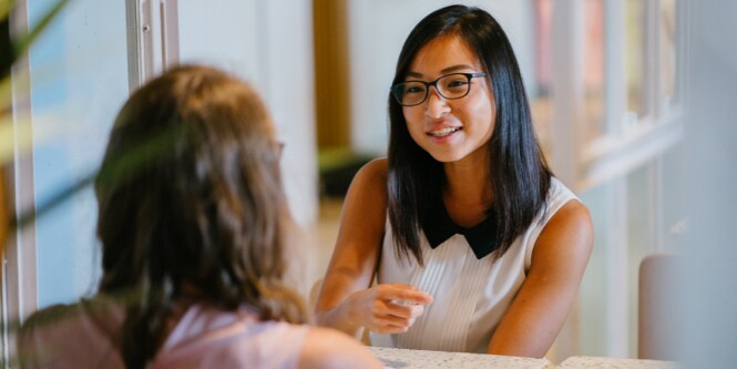Two young women talking in the workplace.
