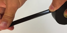 hands stretching tape on roll of Scotch® Vinyl Electrical Tape Super 33+™