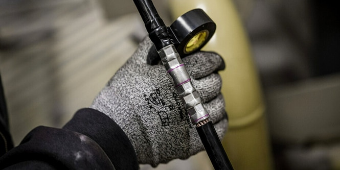 Un trabajador envolviendo un empalme eléctrico de forma irregular con la cinta Super 33+®.
