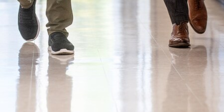 Un primer plano de los pies de dos personas sobre un piso brillante.
