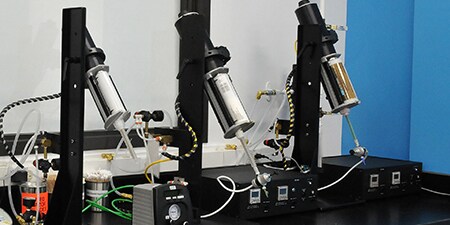 Image of three bench-top dispensers with different adhesive cartridges in place
