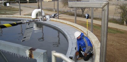 Worker on edge of large tank connected to fall protection anchorage
