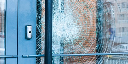 El vidrio roto de una puerta se mantiene en su lugar con una película para ventanas.
