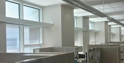 A row of office cubicles face windows covered with 3M™ Daylight Redirecting Film.
