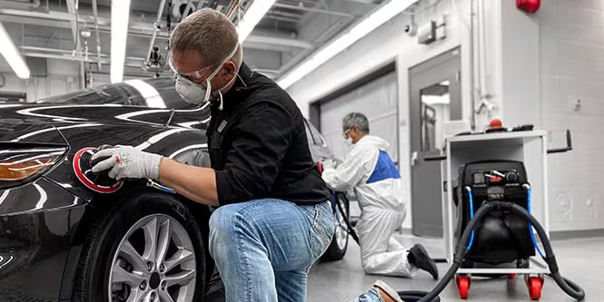 Imagen que muestra a un hombre usando abrasivos de primera calidad con herramientas de primera calidad en un automóvil para lograr resultados excelentes.
