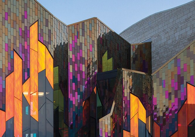 Imagen exterior del edificio con paneles de ventanas en ángulo cubiertos con molduras de vidrio dicroico 3M en tonos cálidos.