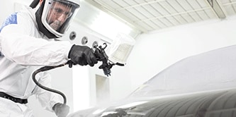 Técnico de pintura pulverizando vehículo.
