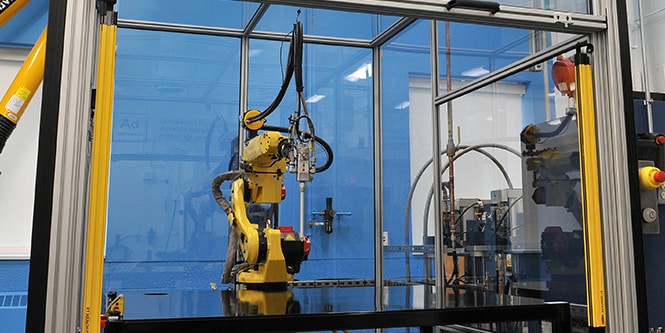 Image of a robot within a workframe, poised over a flat work table
