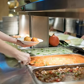 A restaurant worker dishes food from a large pan.