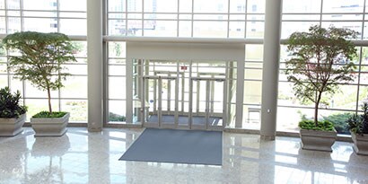 Vestíbulo de edificio de oficinas limpio con puertas correderas y muchas ventanas.

