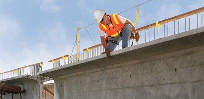 Worker on edge of concrete structure connected to lifeline

