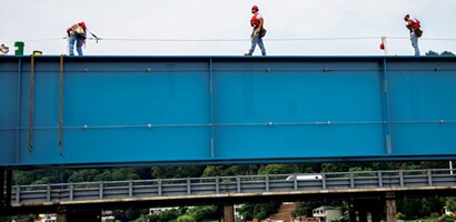 Workers atop steel structure connected to lifeline
