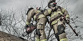 firefighters cutting into a house roof

