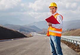 Trabajador de mantenimiento de carreteras de pie en una carretera sin marcar.