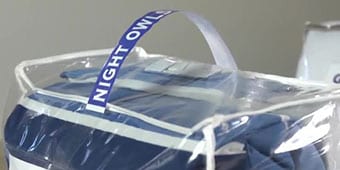 Image of a textile product in a plastic bag with a carry handle attached
