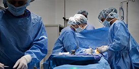 four healthcare professionals working together in a surgery room setting
