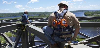 Workers on top of bridge beams secured by all protection gear
