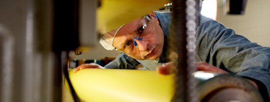Worker inspecting tape on a cylinder
