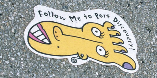 Una película gráfica para aceras muestra un pie de dibujos animados con una cara y unas palabras.
