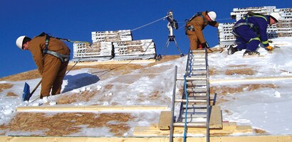 Workers on roof secured by fall protection gear
