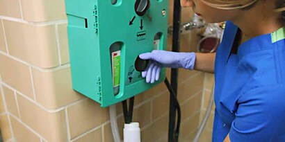 Una persona que lleva guantes y utiliza un sistema de gestión de productos químicos de 3M.
