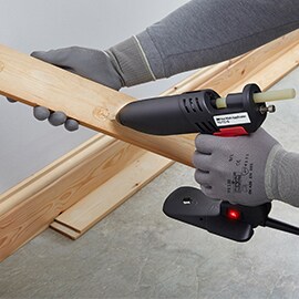 Hot melt adhesive is applied to a piece of wood